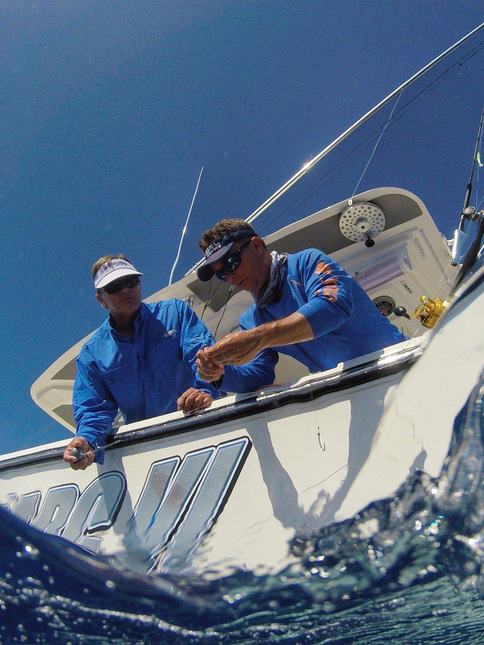 Two men hanging over the back of a boat viewed from the perspective of a fish