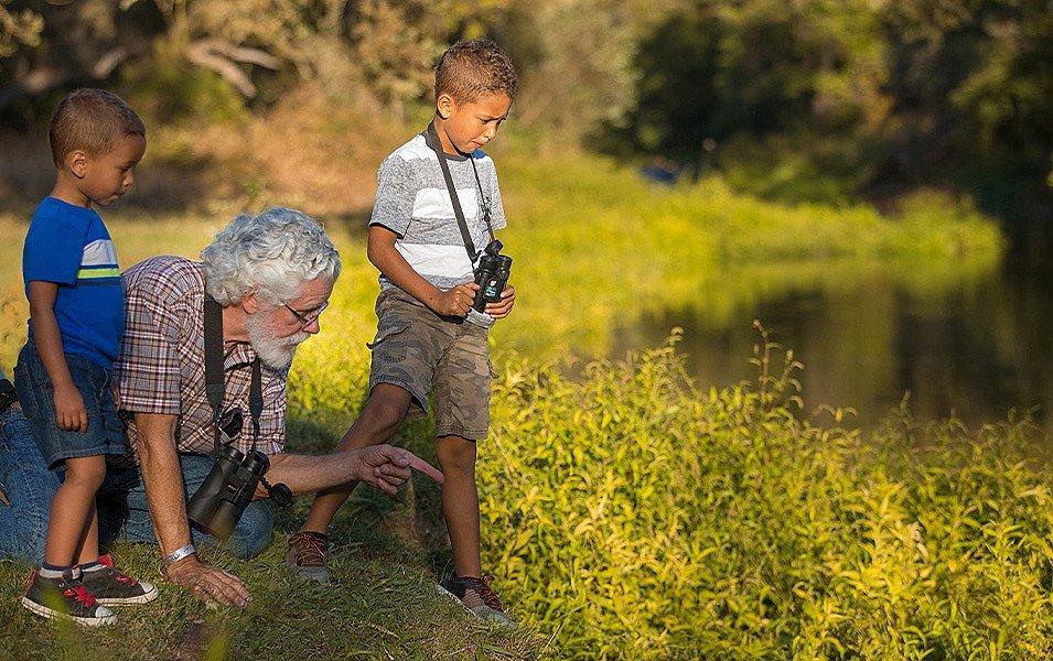 A man teaches two young children about river biology.