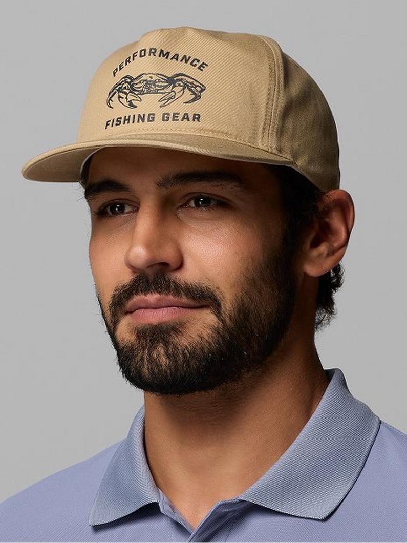 Man wearing tan fishing cap with fish graphic and text on front panel.