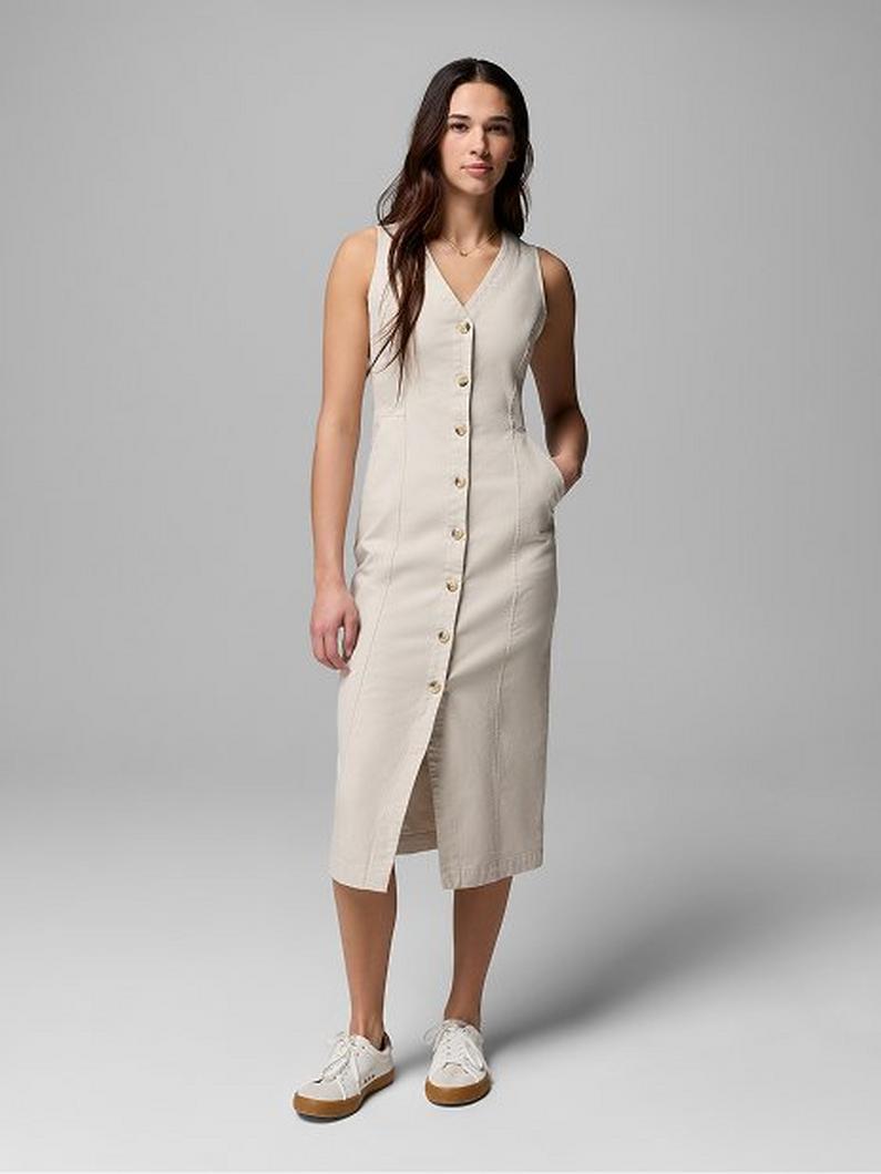Woman wearing sleeveless beige linen button-front midi dress with V-neck and side pockets, paired with white sneakers.
