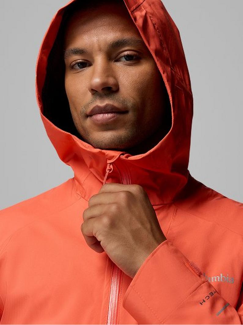 Man wearing orange hooded jacket, hand adjusting zipper near chest.