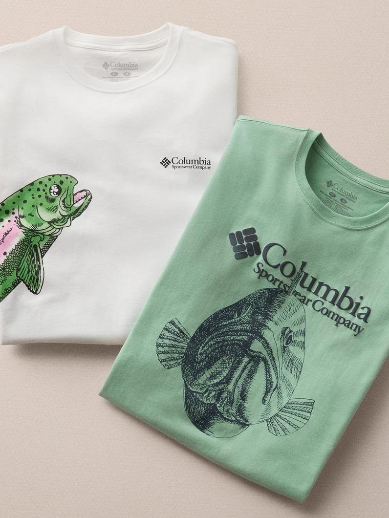 Two folded t-shirts, one white with a colorful fish graphic and one sage green with a bass fish illustration.