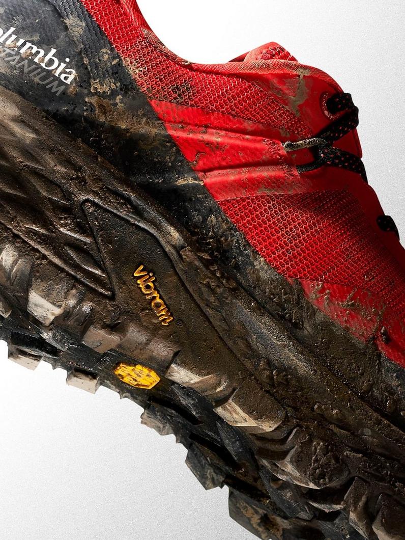 Red and black trail running shoes with muddy soles showing Vibram tread pattern after outdoor use.