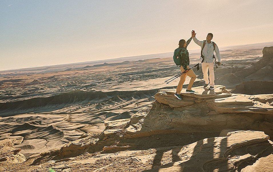 Two hikers celebrate the successful ascent of a high plateau with a high-five. 