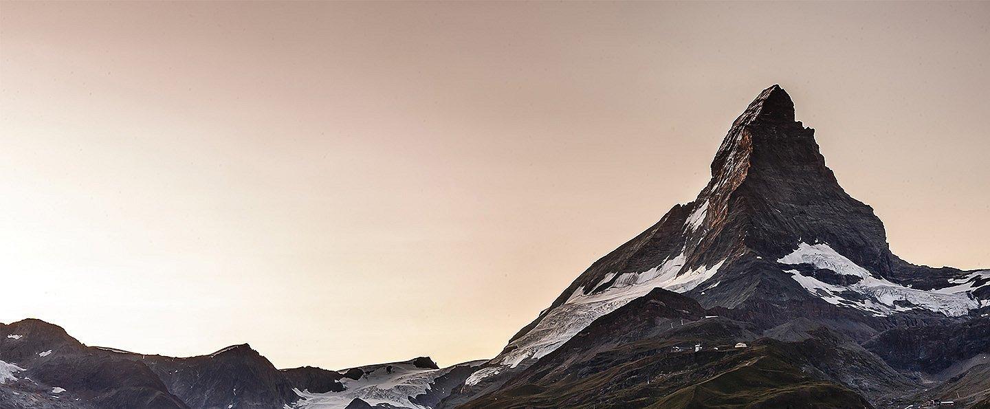 Dramatic photo of steep, pyramid-like peak with glacier field below. 