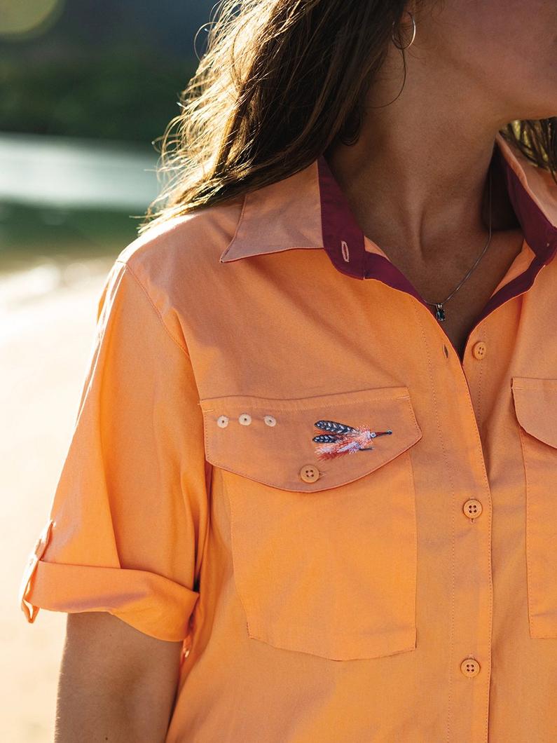 Orange button-up shirt with chest pockets featuring embroidered dragonfly detail and rolled sleeves.