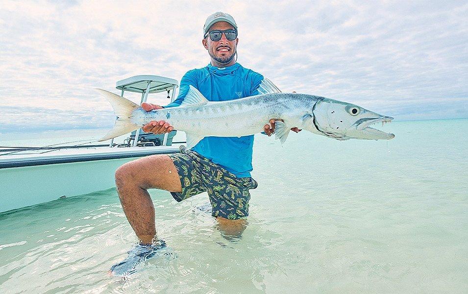 A man wearing PFG fishing apparel displays a large fish before releasing it back into the water.