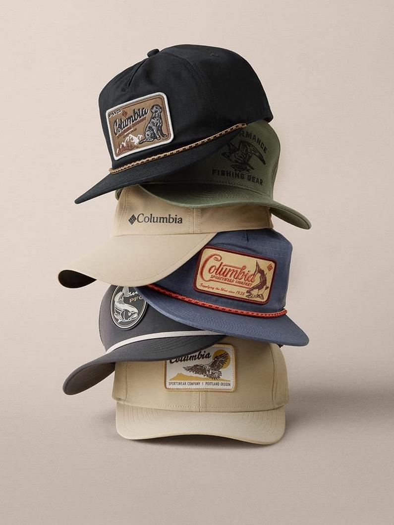 Stack of five baseball caps in various colors with decorative patches featuring outdoor and fishing themes.