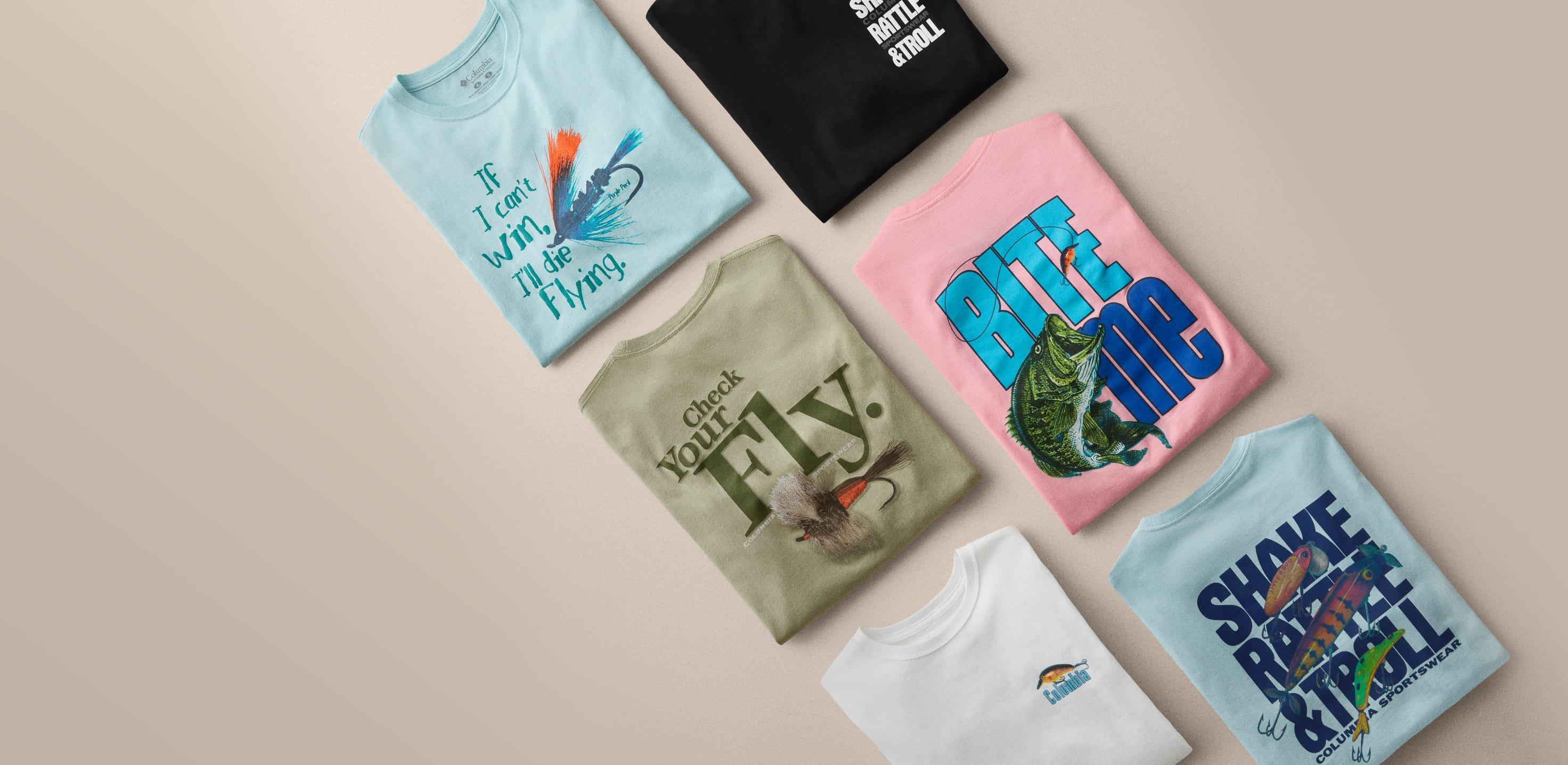 Six folded t-shirts with fishing-themed graphics and text arranged flat on a neutral surface.