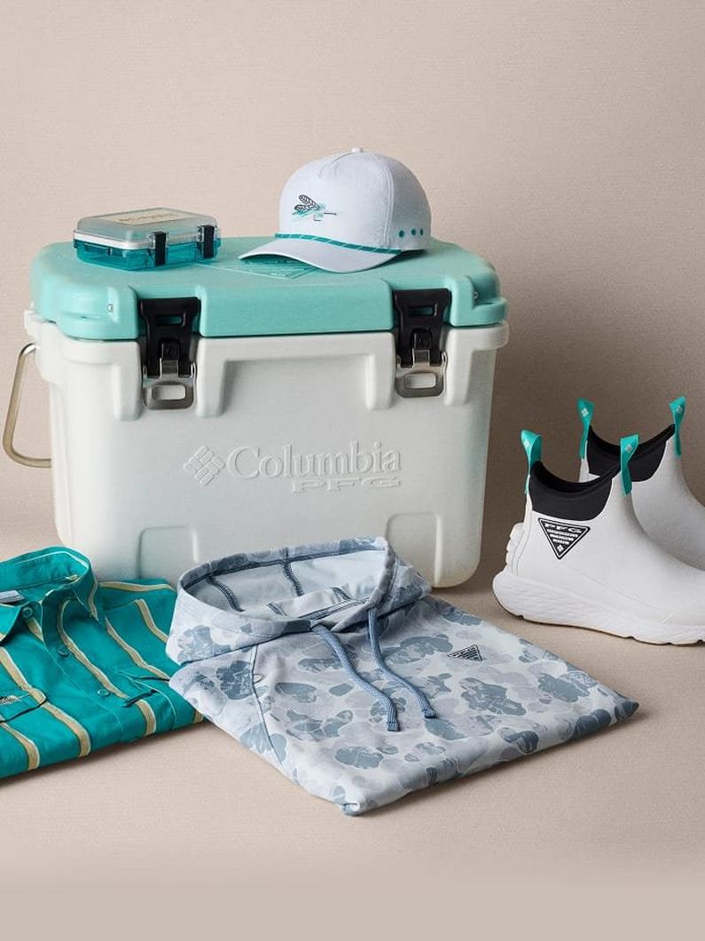 White cooler with turquoise lid displaying fishing gear: cap, tackle box, folded shirt, and water shoes.