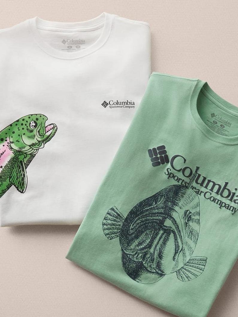 Two folded t-shirts featuring fish graphics, one white with a colorful spotted fish and one green with a detailed fish illustration.