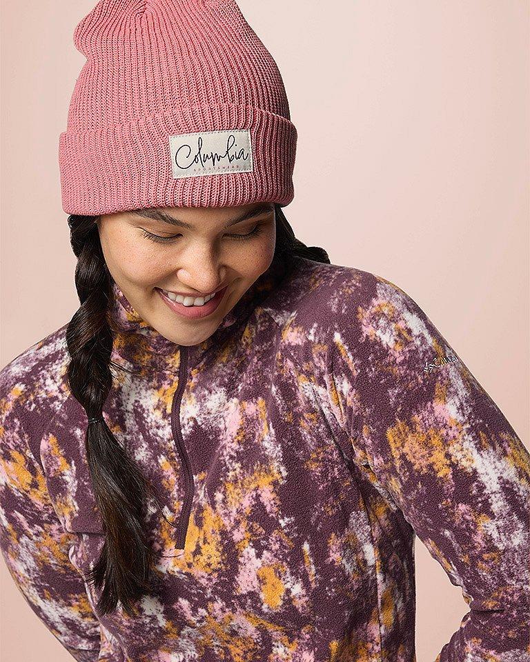 A woman smiling in a beanie and cozy fleece jacket.
