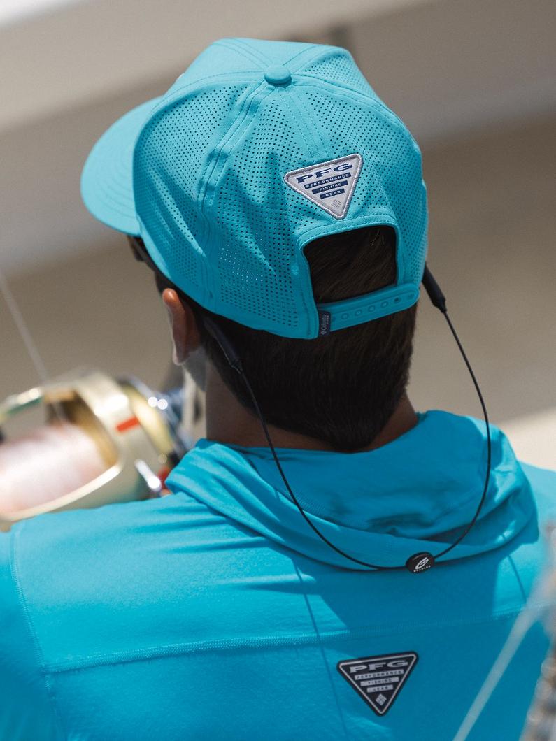 Person wearing turquoise perforated mesh cap and matching fishing shirt with adjustable hat strap.