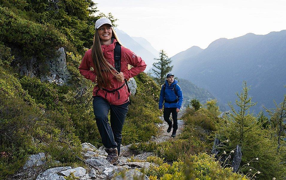 A man and a woman, wearing Columbia Titanium jackets, hiking up a rocky mountain path. 