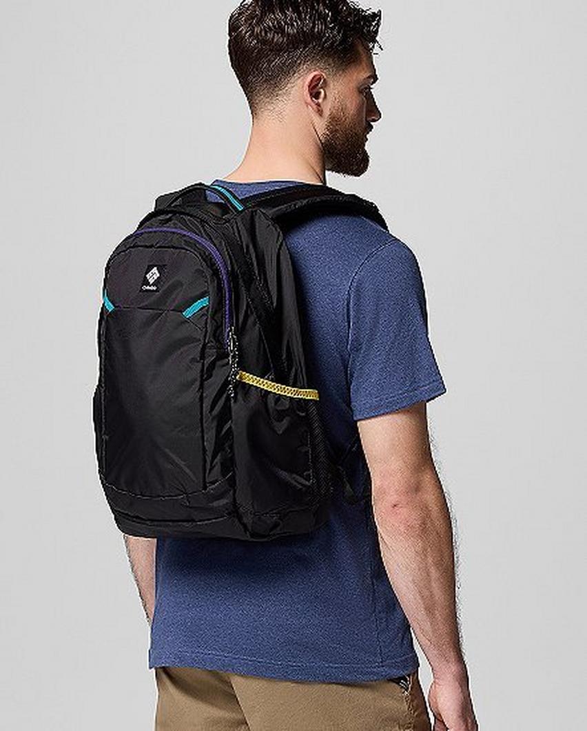 ⁨A man facing away from the camera wearing a blue backpack.