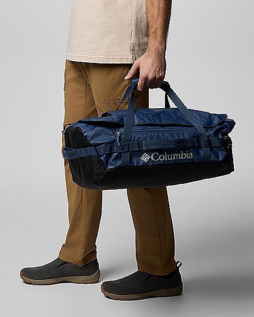 Waist-down image of a man carrying a blue duffel bag.