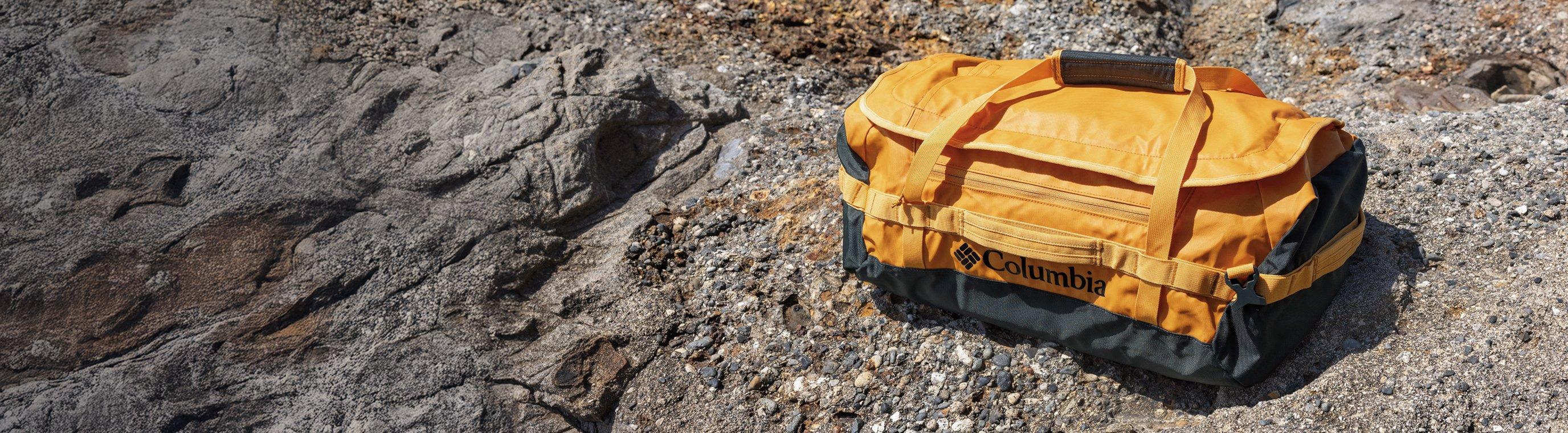 A yellow duffel bag on rocky terrain.