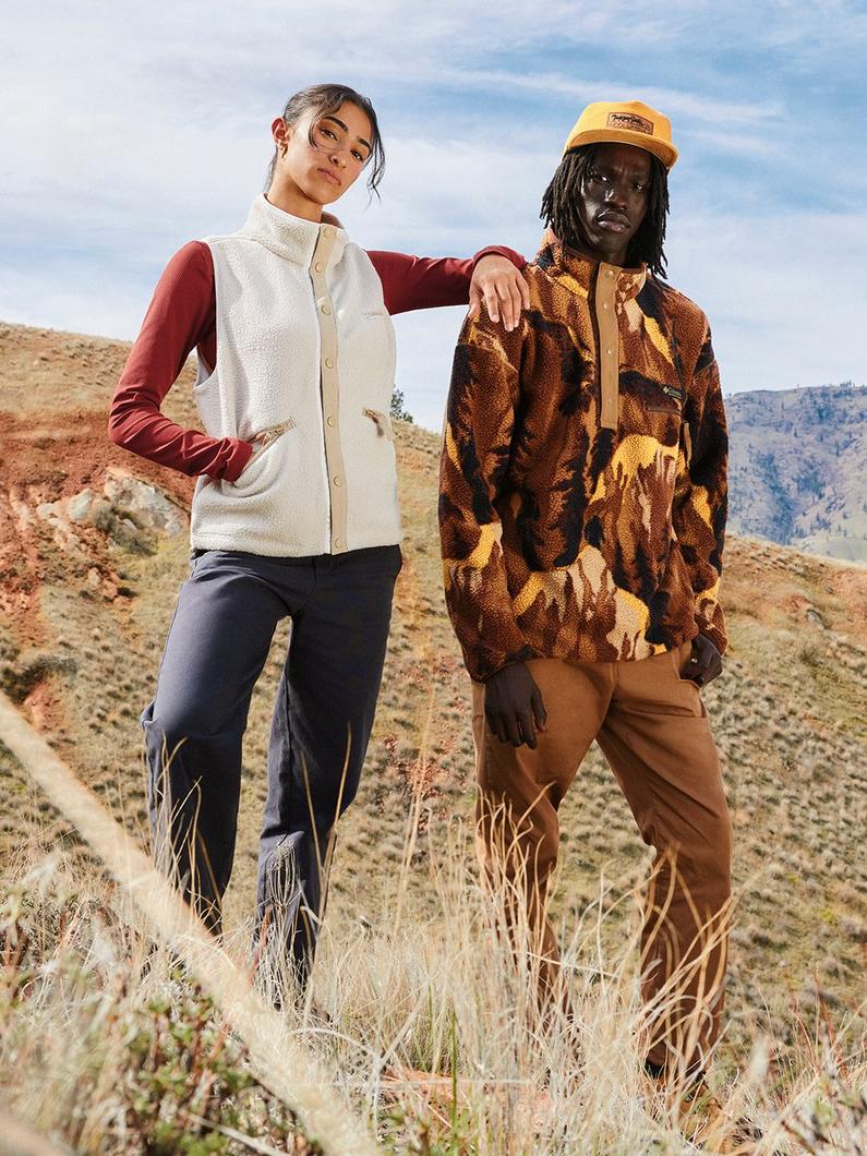Two models posing outdoors in fleece outerwear, one in cream vest with burgundy sleeves, one in patterned jacket.