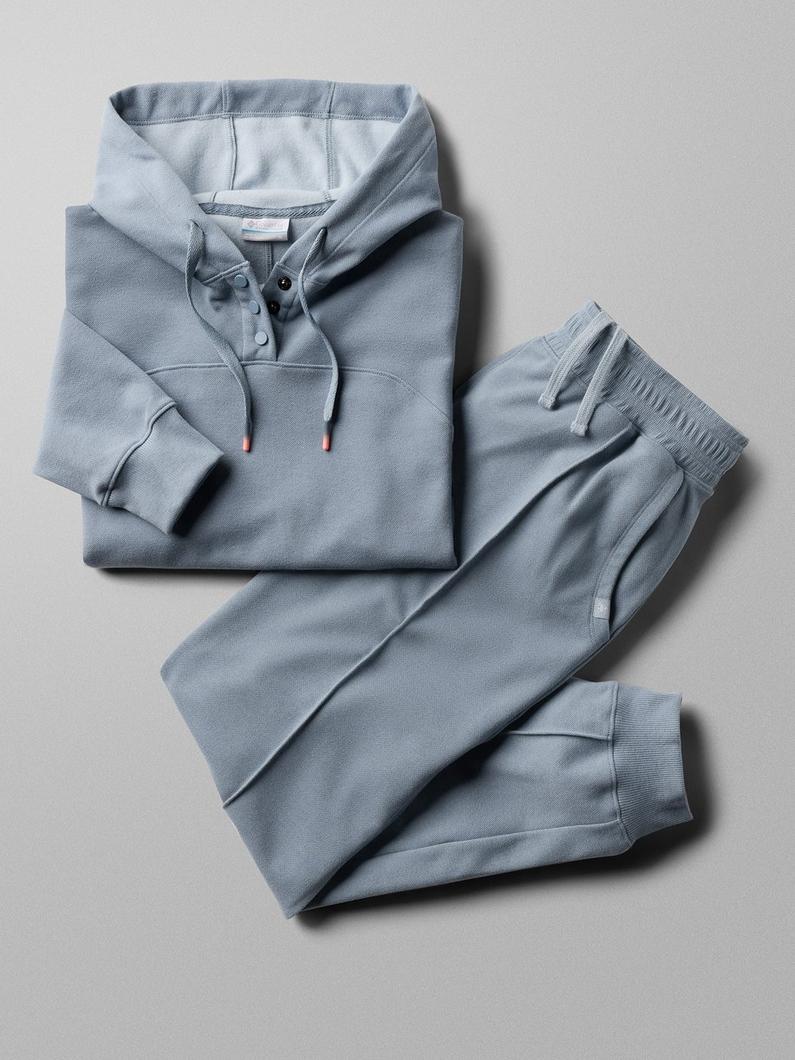 Light blue-gray hoodie and matching joggers laid flat, featuring drawstring hood and elastic cuffs.