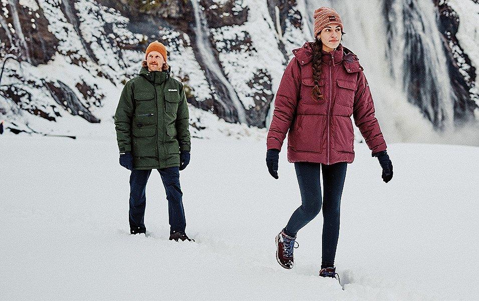 Man wearing Columbia Hiking pants and woman wearing Columbia hiking leggings walking in the snow.  