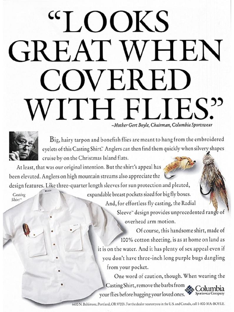 White fishing shirt with embroidered eyelets for holding flies, displayed with fishing fly lures.