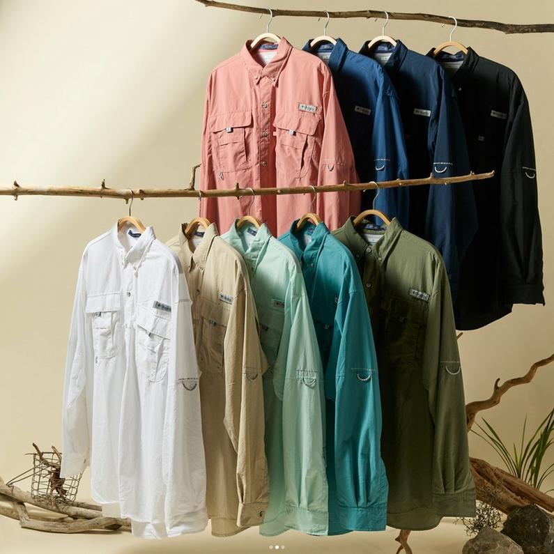 Collection of long-sleeve fishing shirts in various colors hanging on branch rods displayed in two rows.