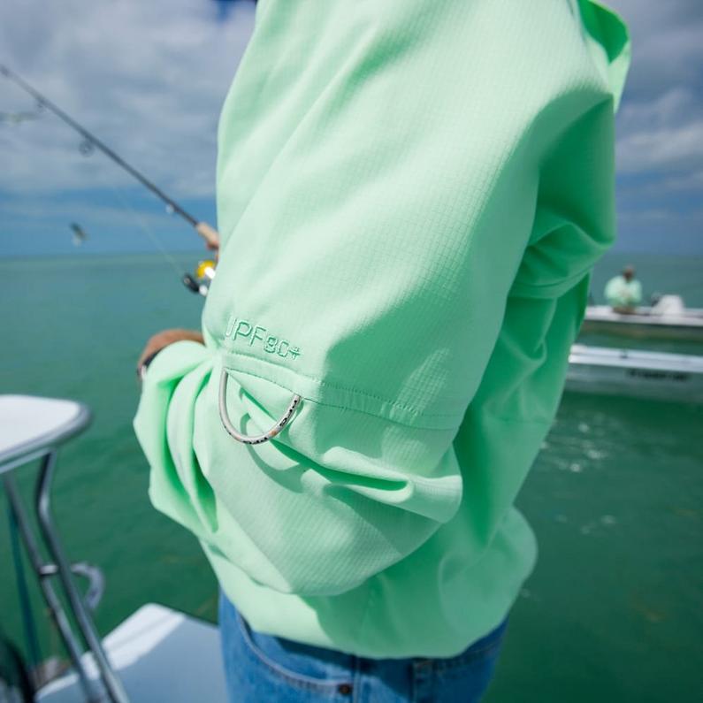 Person wearing mint green long-sleeve fishing shirt with UPF 80+ sun protection while holding fishing rod on boat.