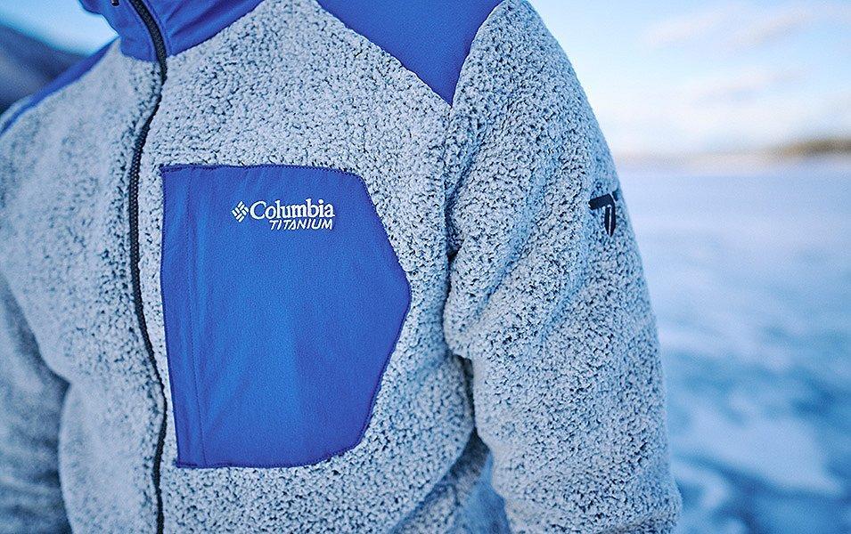A close up of a person wearing a Columbia Titanium fleece jacket with a zippered chest pocket. The jacket's fleece is light blue and fluffy.