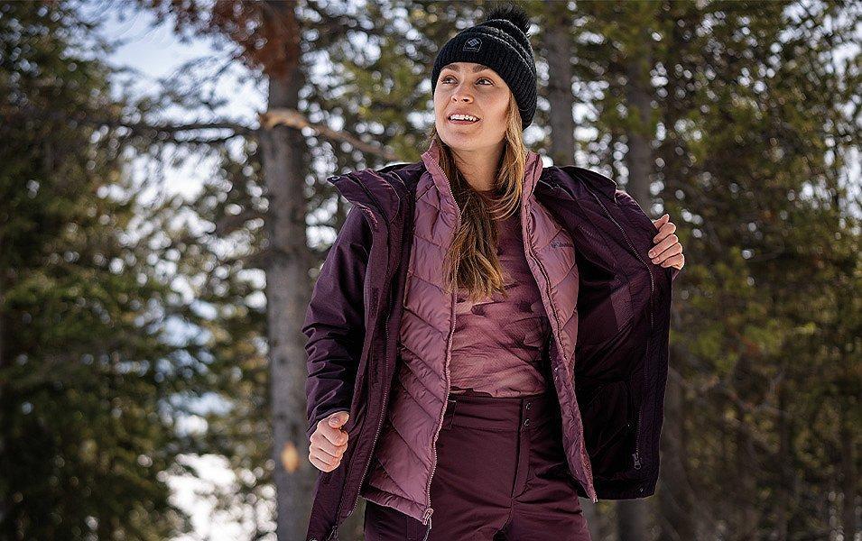 A woman wearing a Columbia 3-in-1 Interchange parka demonstrates how the quilted lining can be worn separately from the waterproof shell.