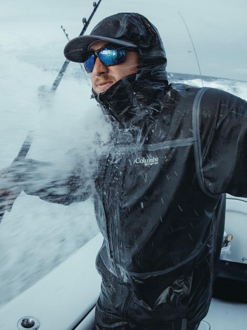 An angler on the ocean wearing a black rain jacket.