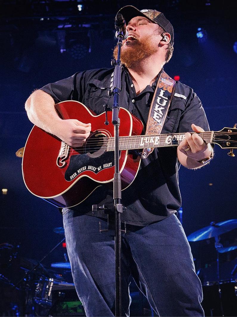 Artist Luke Combs playing the guitar and singing.