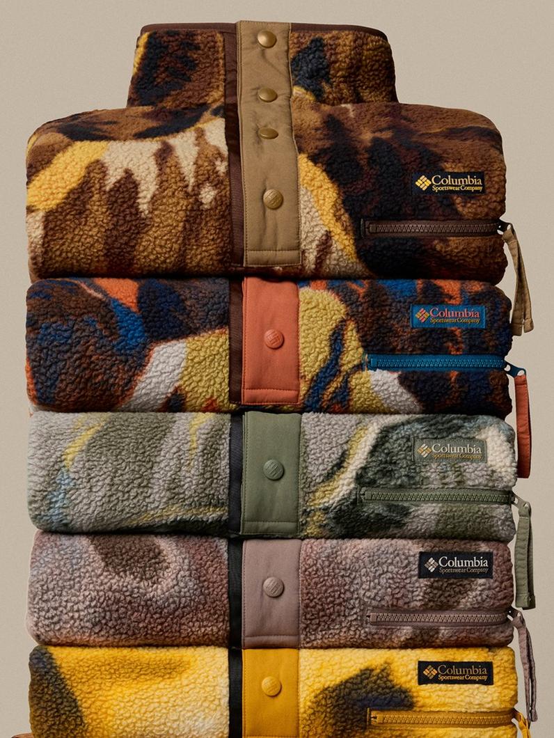 Five fleece jackets stacked vertically in various patterns and colors with snap button closures and zippered pockets.