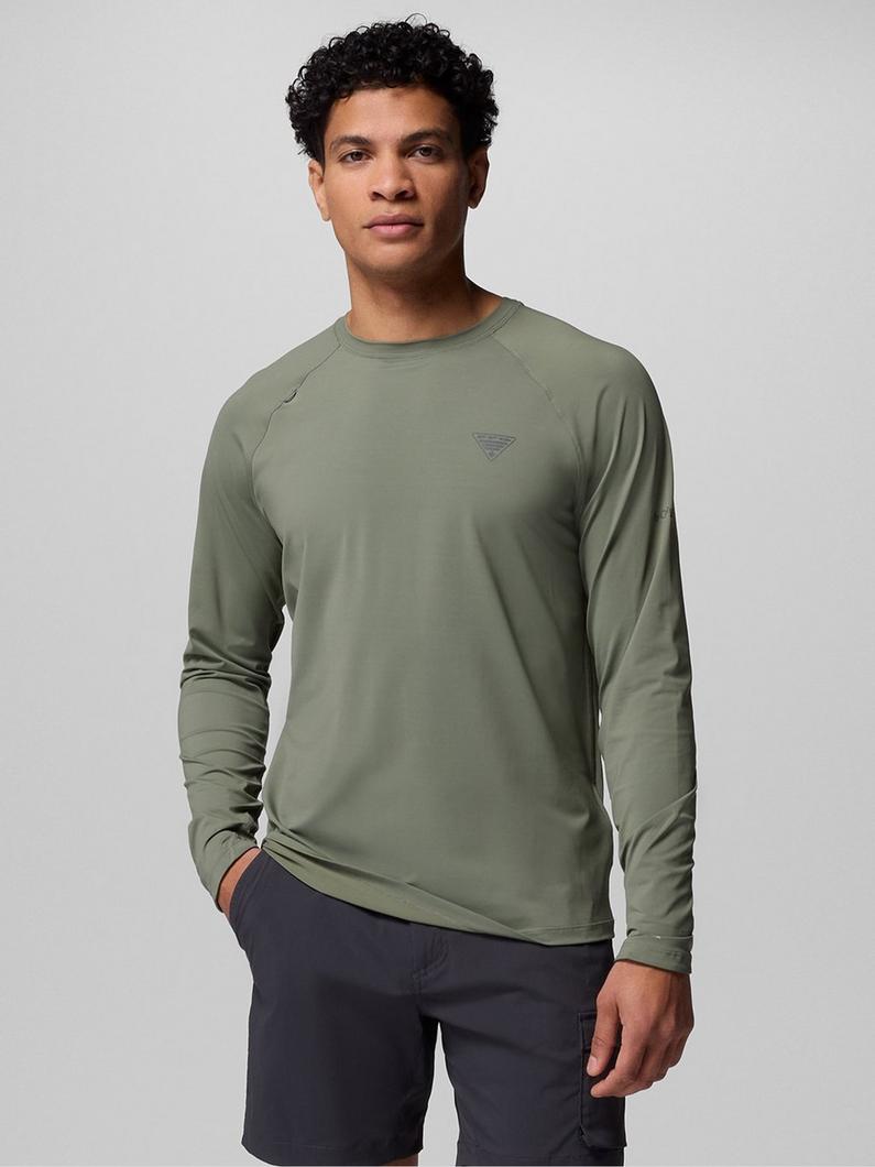 Man wearing olive green long-sleeve athletic shirt with raglan sleeves and dark navy shorts.
