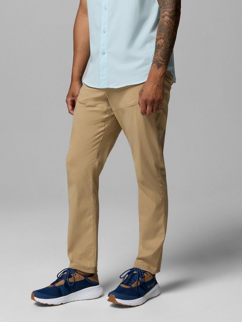 Man wearing light blue button-up shirt, tan pants, and navy blue athletic shoes with white soles.