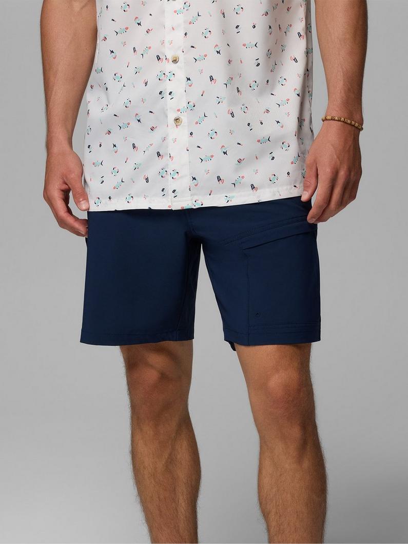 Man wearing white short-sleeve shirt with colorful confetti print pattern and navy blue shorts.
