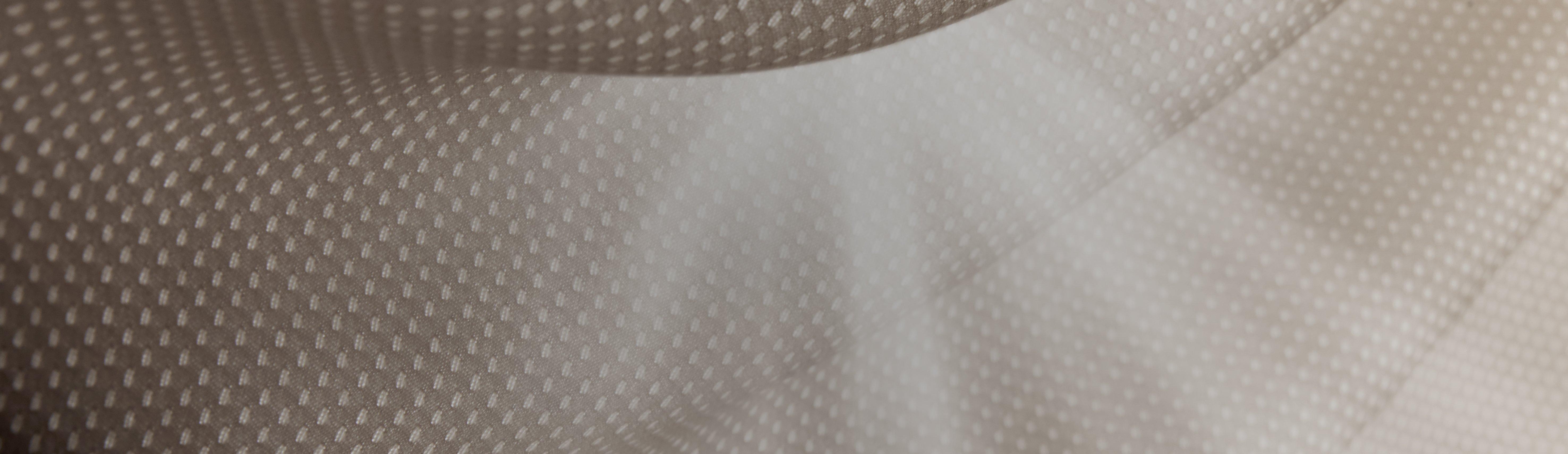 Close-up of gray textured mesh fabric with raised dot pattern and smooth center panel.