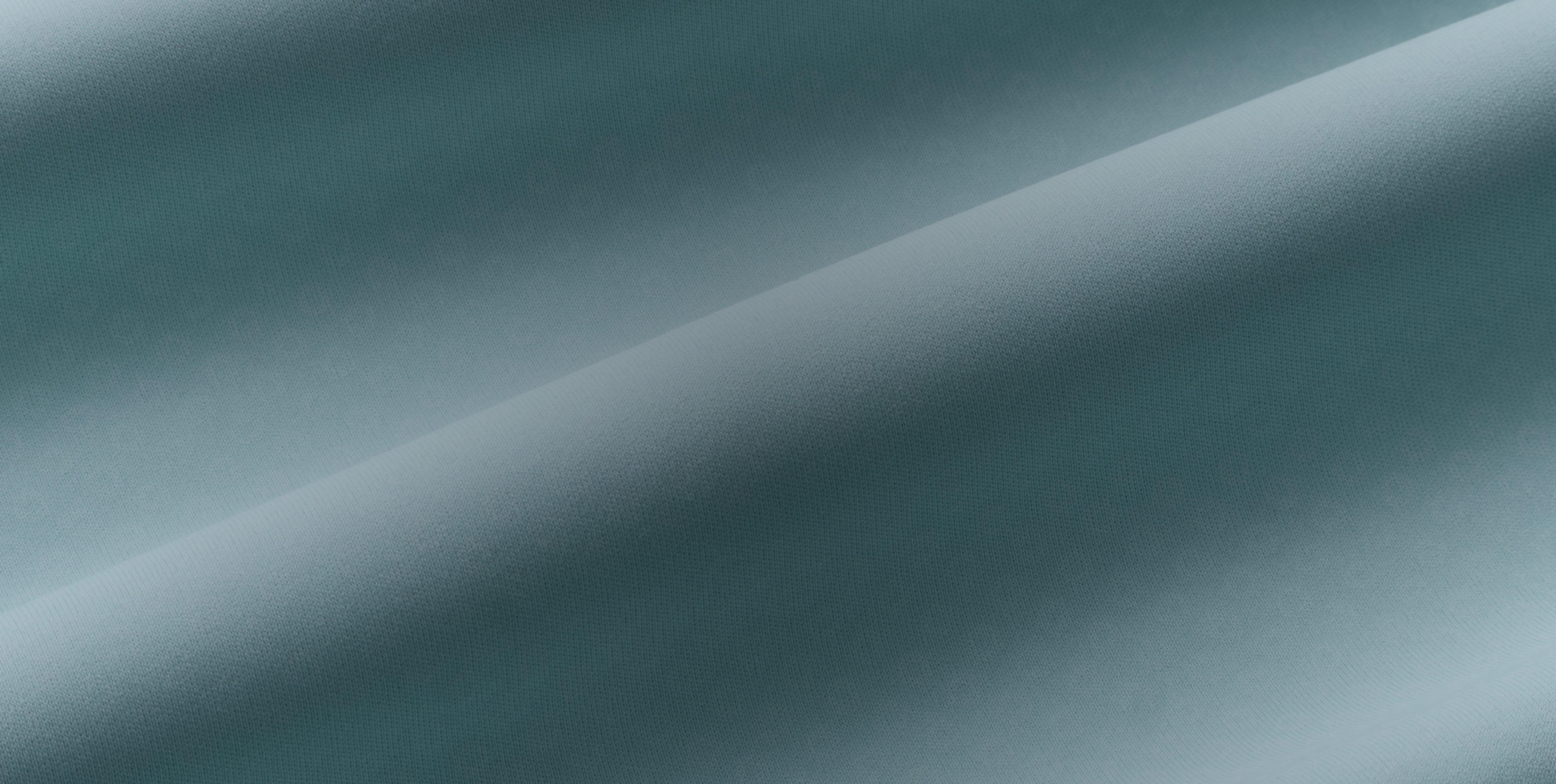 Close-up of smooth teal fabric with soft folds and a subtle textured weave.