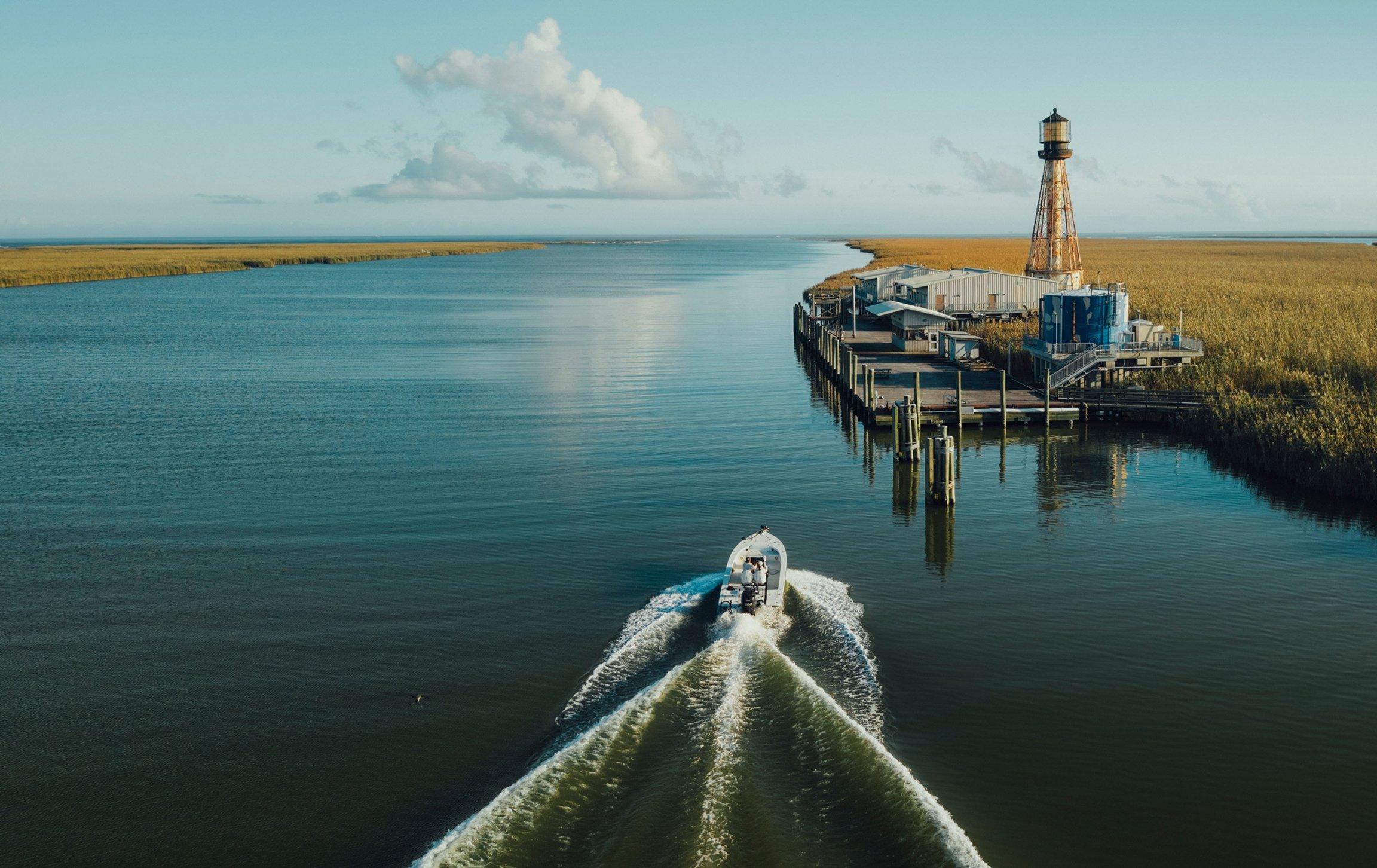 Anglers in a boat on a scenic waterway.