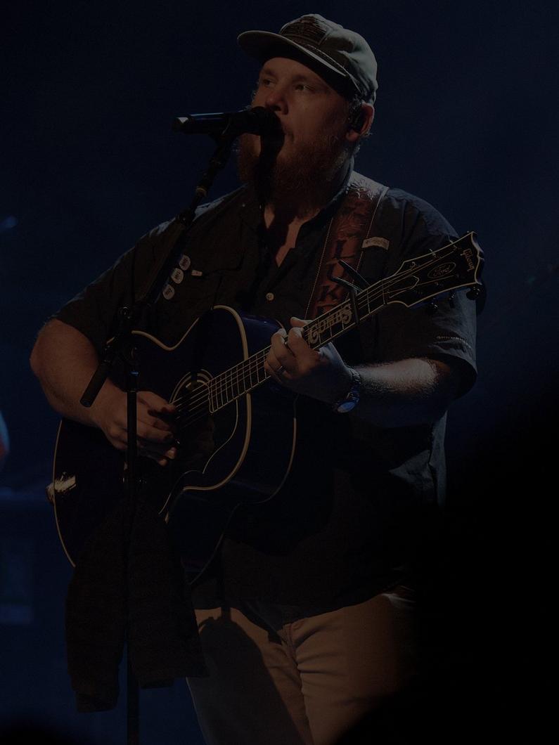 Musician Luke Combs performing on stage in a Bahama shirt.