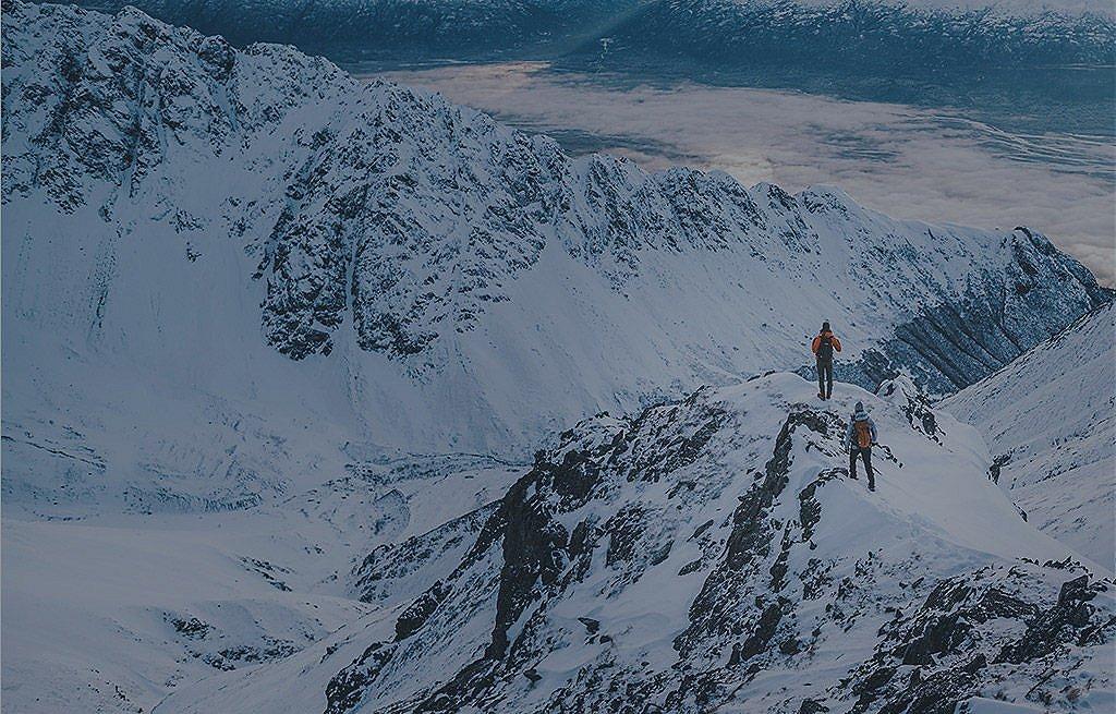  Two people in Columbia gear hiking in a snow-covered mountain range. 