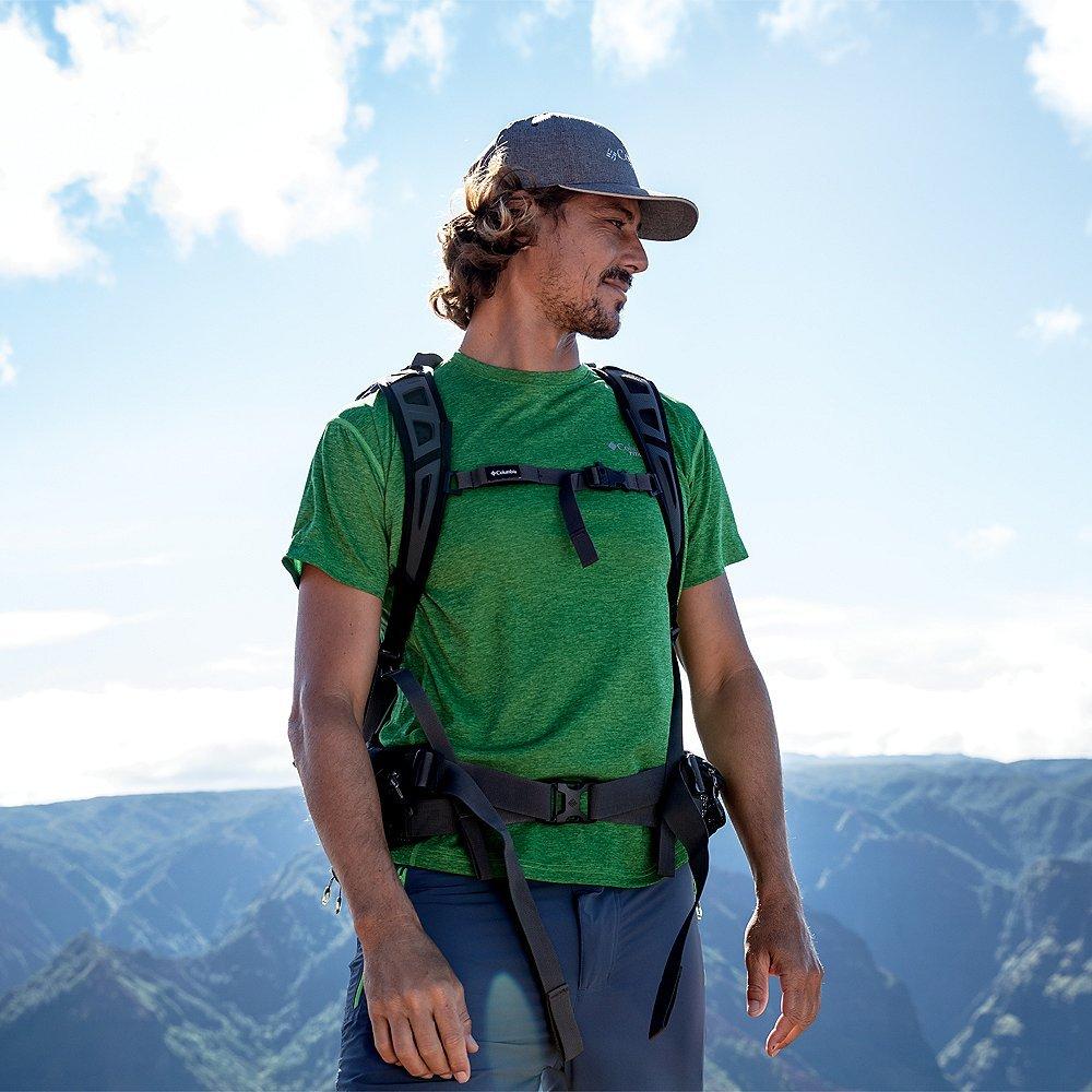 A man standing before a background of mountains
