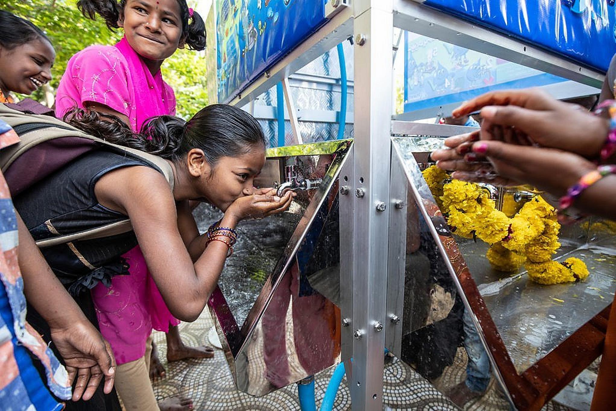 Girl drinking fresh water from a tower of clean water.