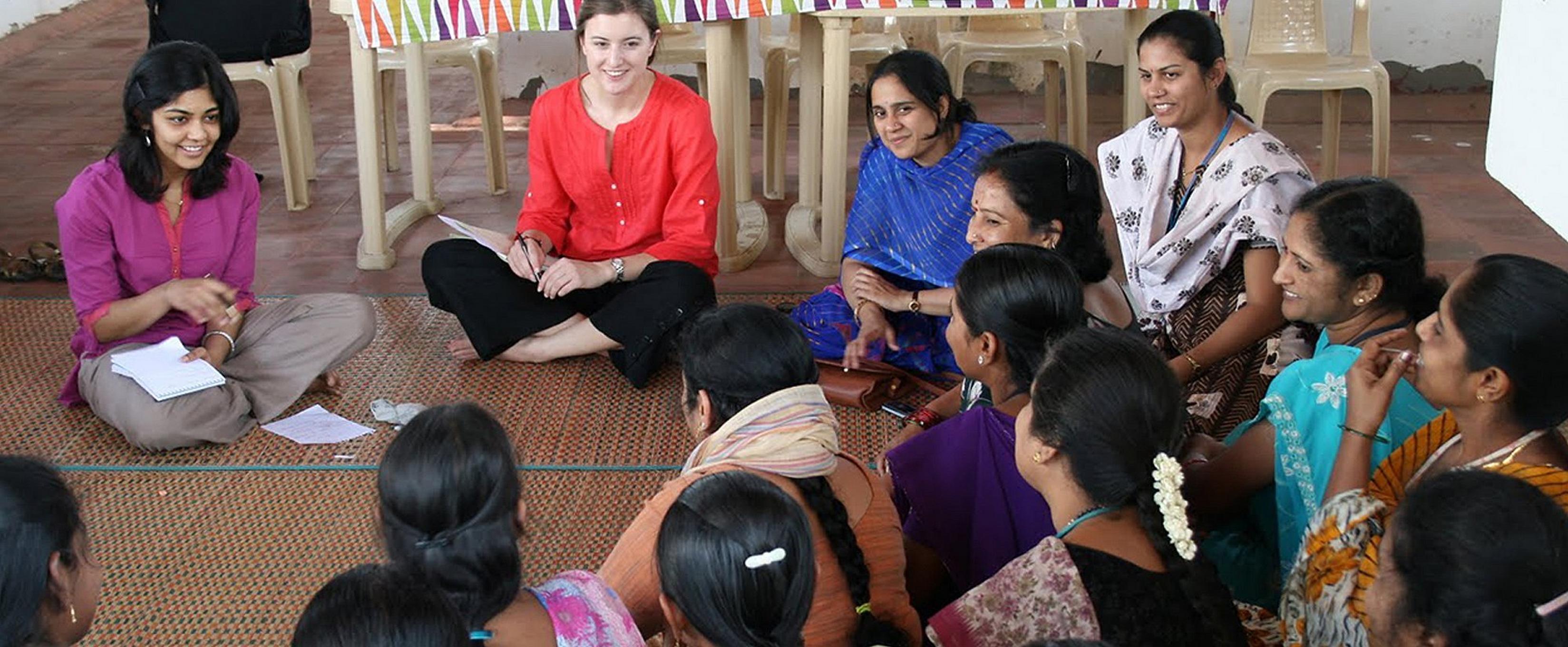 Group of women sitting on a classroom floor in a circle talking