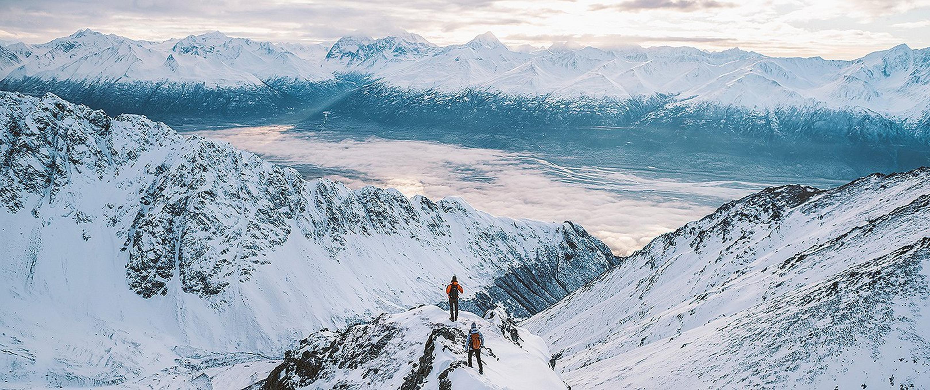 Two people hiking on a snowey ridge
