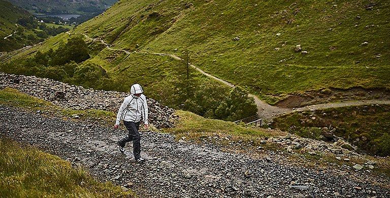A person wearing an OutDry Extreme Eco jacket walking up a stony path.