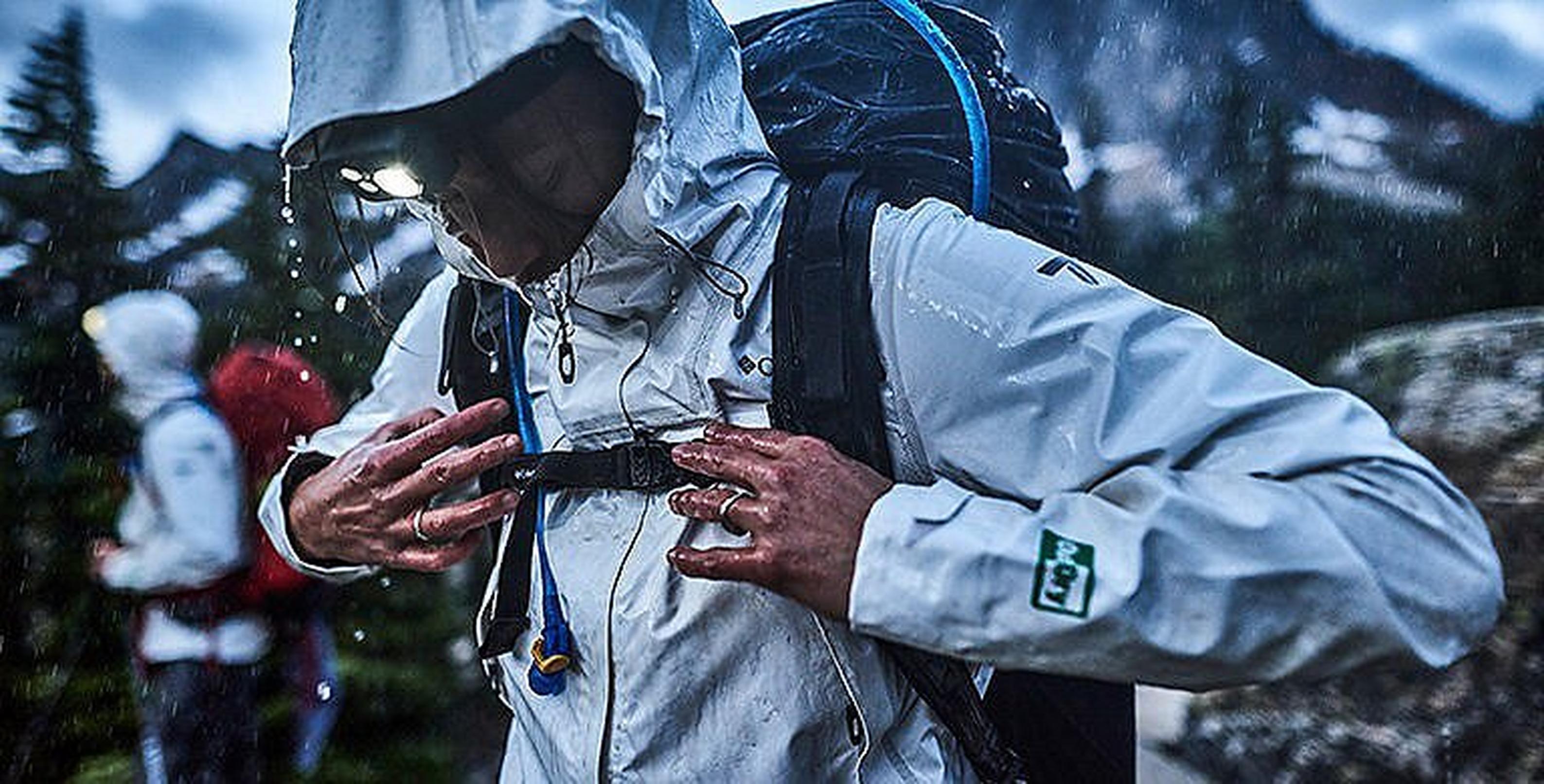 Person in a white waterproof jacket with water falling off the brim of the hood.