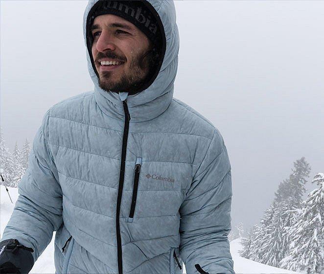 A smiling man stands in the snowy wilderness wearing an RDS-certified down jacket. 