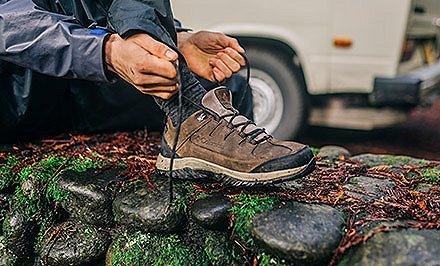 A man lacing up a hiking shoe with TechLite cushioning.