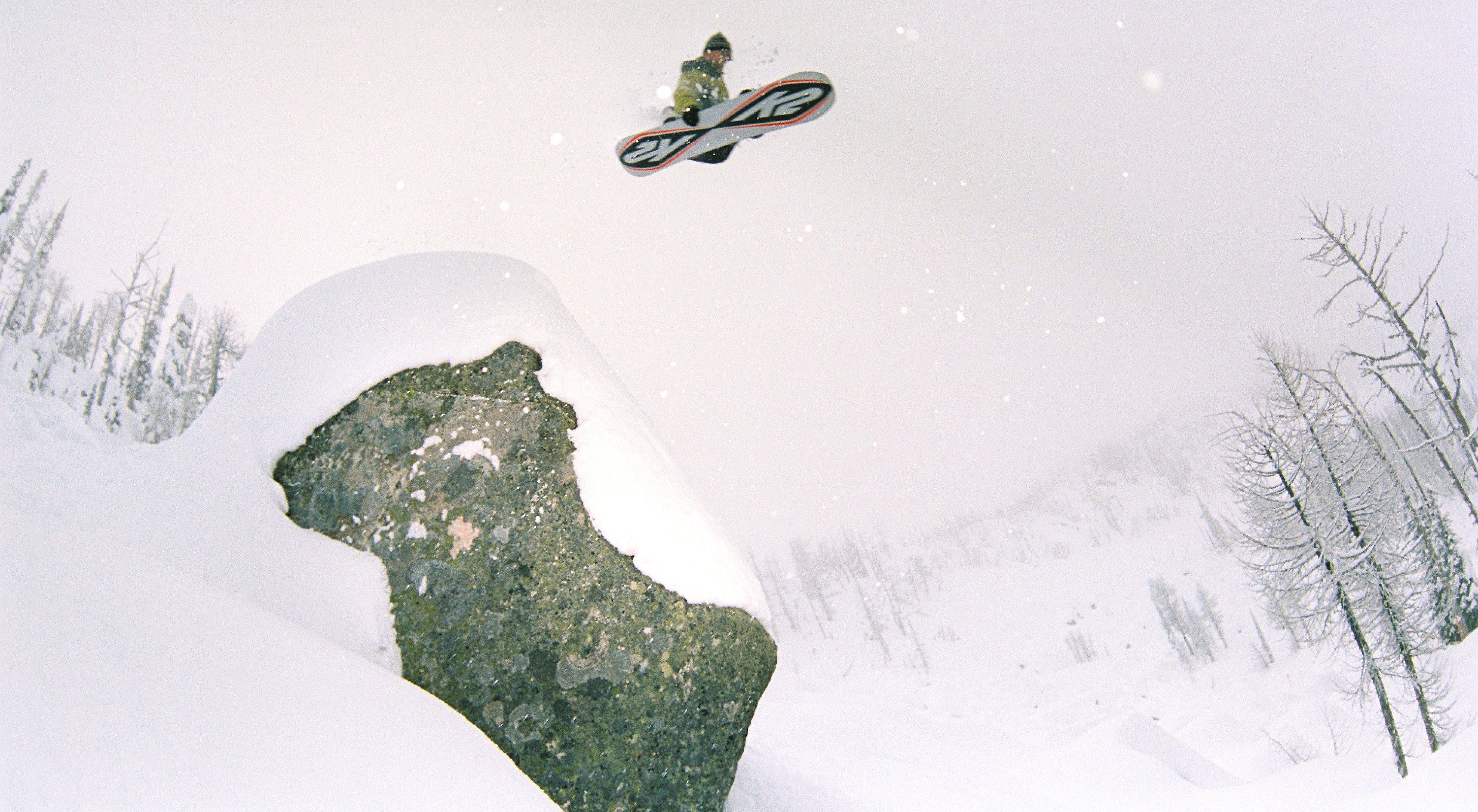 Jake jumping off a snowy cliff on his snowboard.