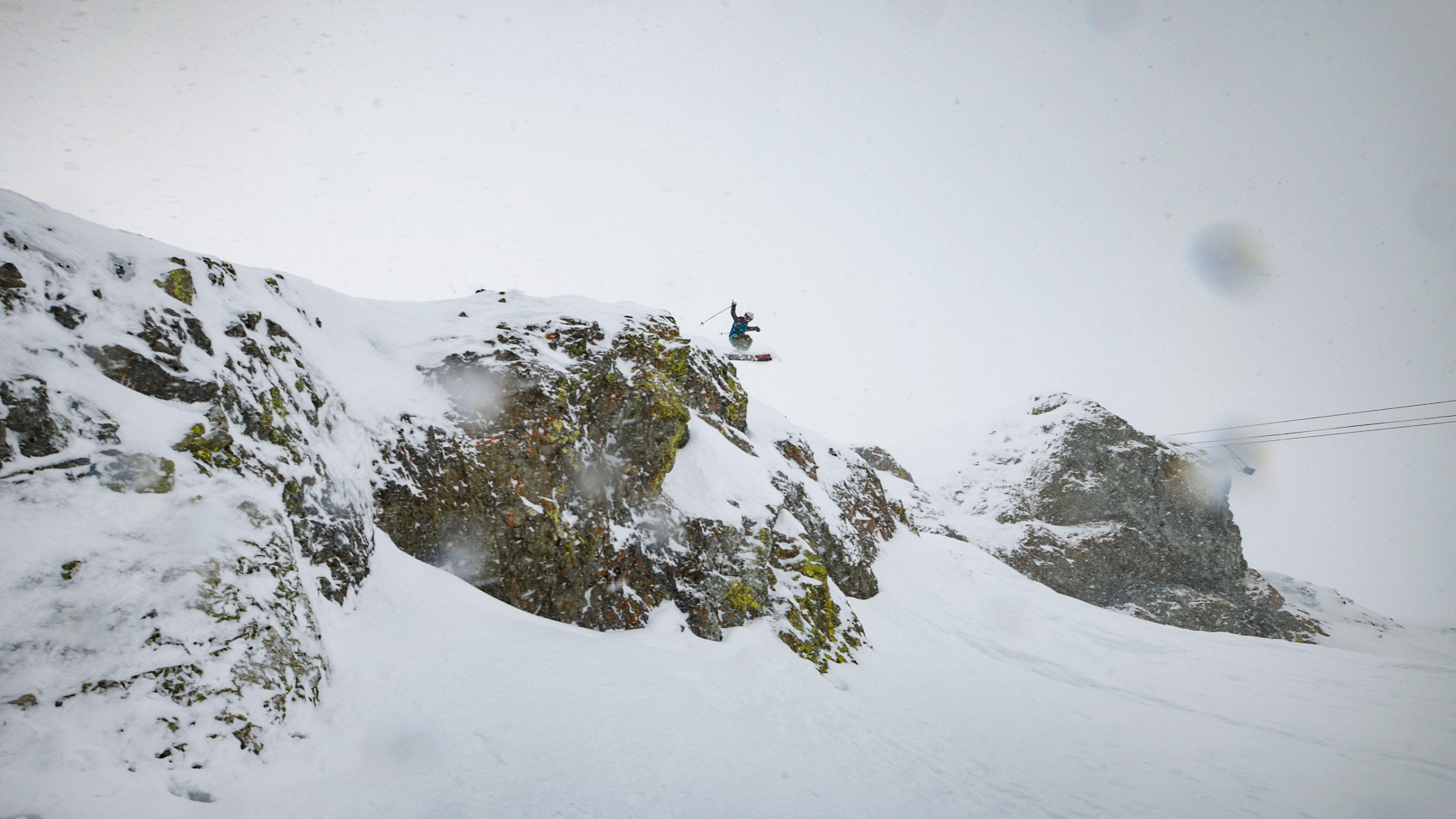 Lily getting air on a snowy cliff